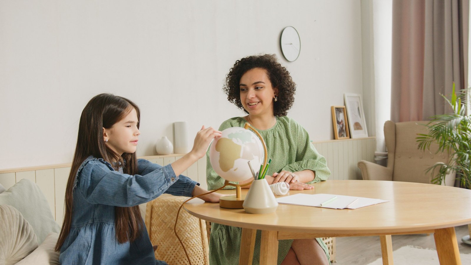 A child studies a globe with a teacher, engaging in an educational activity.